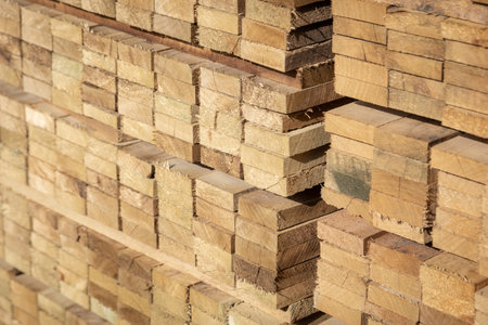 Stacked wooden planks in a lumberyard, various shades and textures, neatly arranged.の写真素材
