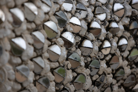 close-up of a textured surface covered in numerous small, silver, semi-circular mirrors embedded in...