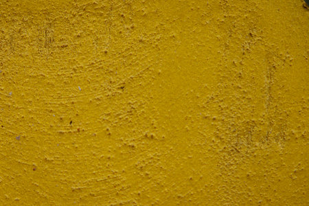 close-up shot of a textured gold yellow concrete surface. The rough and slightly uneven texture, along with subtle variations in the gold yellow hue, creates a visually interesting background. Some subtle horizontal lines are visible.の写真素材