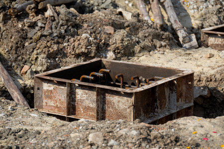 Close-up of a concrete foundation with a steel rebar cage inside, prepared for construction. Shows...