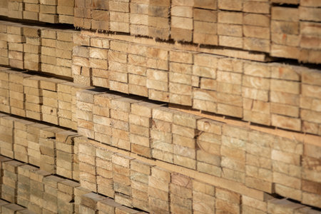 Stacked wooden planks in a lumberyard, various shades and textures, neatly arranged.