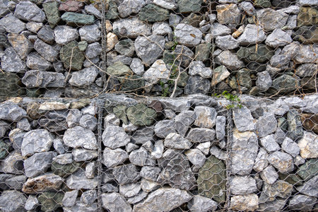 gabion wall, showcasing the texture of the grey stones and the wire mesh. The image highlights the...