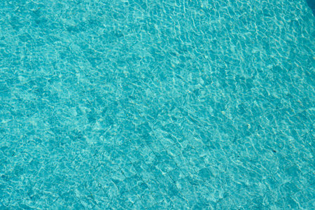 Vibrant blue water surface with shimmering reflections and ripples under sunlight.