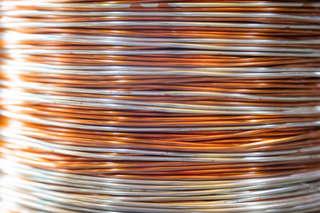 Close-up shot of stacked metallic wire coils showcasing their intricate patterns and reflective surfaces. The image captures the interplay of light and shadow on the tightly wound wires, emphasizing the precision and craftsmanship in industrial material production.の写真素材