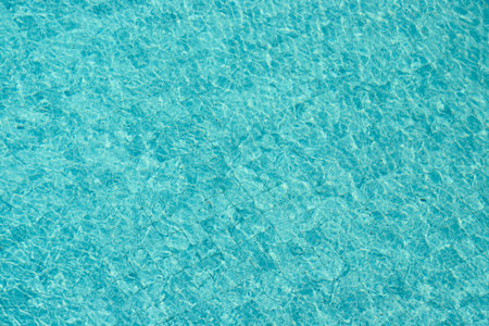 Vibrant blue water surface with shimmering reflections and ripples under sunlight.