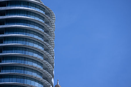 A section of a modern building with many rectangular glass windows reflecting the clear, bright blue sky.の写真素材