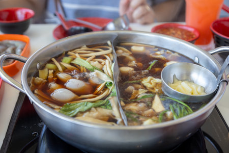 bubbling hot pot filled with a variety of ingredients, including vegetables, noodles, and meat. The...