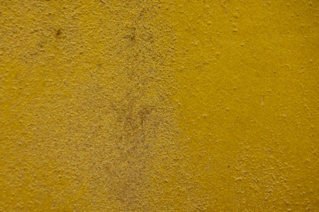 close-up shot of a textured gold yellow concrete surface. The rough and slightly uneven texture,...