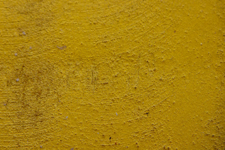 close-up shot of a textured gold yellow concrete surface. The rough and slightly uneven texture, along with subtle variations in the gold yellow hue, creates a visually interesting background. Some subtle horizontal lines are visible.の写真素材