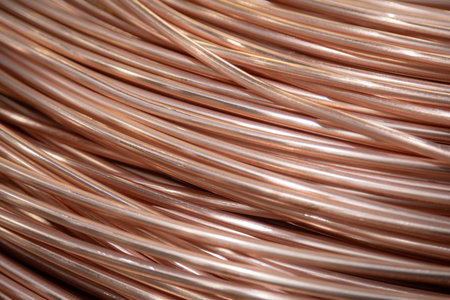 Close-up of coiled copper wires with a shiny surface, intricate overlapping pattern, warm lighting.
