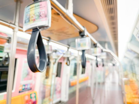 Blurred view of an empty subway train interior with bright yellow seats and stainless steel poles. The modern train car is well-lit, featuring overhead handles and smooth, clean floors, suggesting public transportation in motion.の写真素材