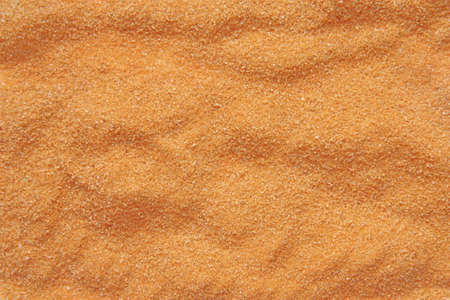 Orange sand lays waves and many grains of sand are visibleの写真素材