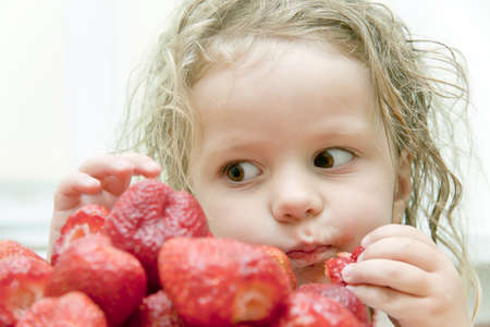 child greedy eats a strawberryの写真素材