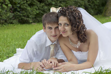 Happy newly-married couple lies on a grassの写真素材