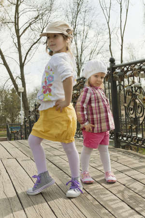 Two sisters pose on the wooden bridge in park in the autumnの写真素材