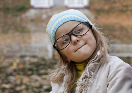 little girl in points sits in park and has bitten a lipの写真素材
