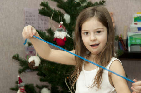 girl decorates a fur-tree and has control over a garlandの写真素材