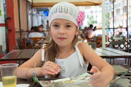 elegant girl has stopped to eat in street cafeの写真素材