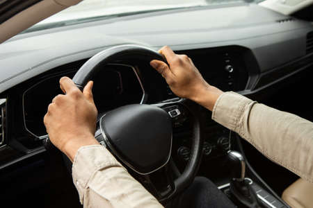 Two hands hold the steering wheel inside the car.