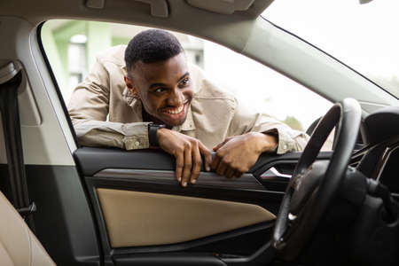Black guy looks at the interior of the car, choosing a new car Selective Focus
