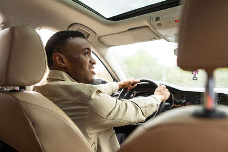 African american man driving modern car smiling