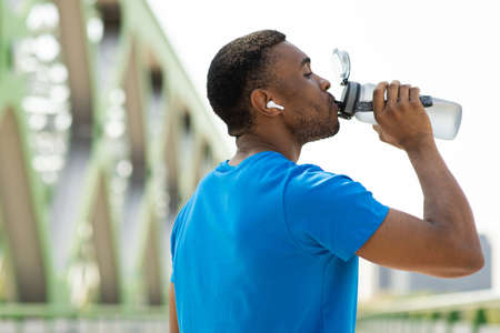 The benefits of hydration. Portrait of a young black man drinking water from a sports bottle after...