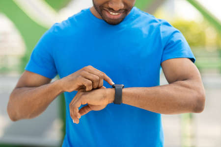 Black sports guy is training with a blurred background in the park, modern technology and an active...