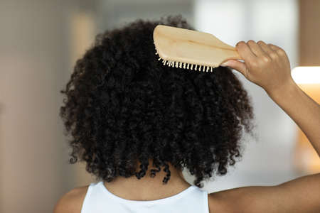 Rear view of a lady combing her hair with a wooden comb. Selective Focusの写真素材