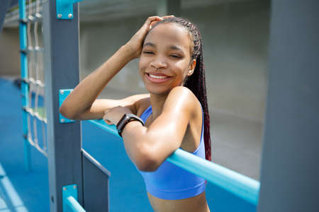 Black fitness woman looking at camera and smiling at sports field.の写真素材