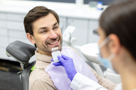 Female dentist applying tooth scale samples set to smiling male patient of dental clinic, closeup shotの写真素材