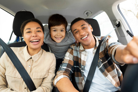 Excited family of three sitting in new car driving and enjoying road trip on vacation, parents and son posing and smiling at camera in autoの写真素材