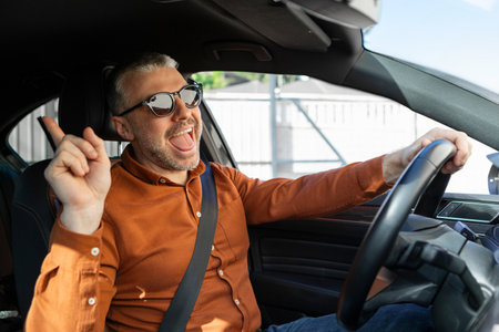 Overjoyed middle aged man in casual outfit enjoying car ride alone, listening to music, singing...