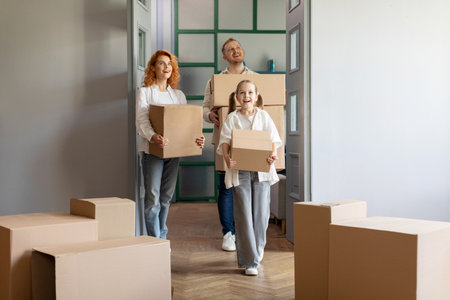 Happy family carrying cardboard boxes together, helping each other in their new home on moving day,...