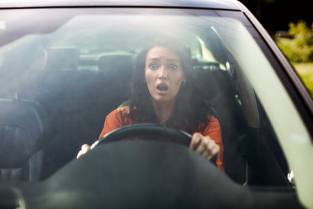 Front view portrait of scared woman driving car before an accident and looking with frightened facial expressionの写真素材