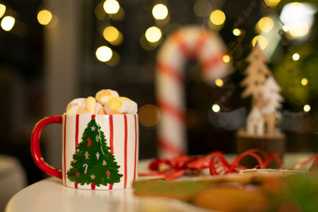 Focus on mug of delicious cocoa decorated with marshmallows on table with Christmas decorations on background, free spaceの写真素材