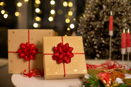 Two wrapped presents on table and Christmas tree on background with holiday decorations and bokeh lights glowing in eveningの写真素材