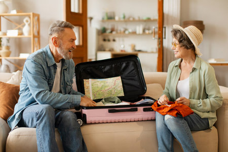 Elderly couple packing suitcase for vacation, senior husband and wife talking while preparing for...
