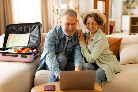 Happy senior couple planning vacation travel with laptop, booking tickets or hotel accommodation on...