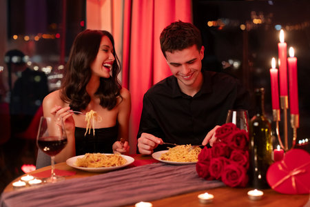Handsome man and pretty woman dinning at restaurant, celebrating Valentines Day together, lovers enjoying romantic festive meal in the eveningの写真素材