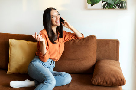 Pleasant call. Happy lady talking on cellphone at home and smiling, enjoying mobile phone...