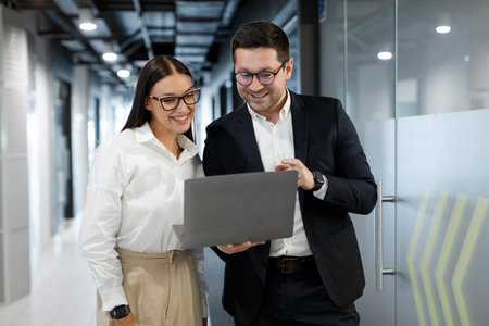 Positive businesspeople collaborating on laptop computer, brainstorming over company startup, motivated colleagues looking at laptop screen discussing business ideas togetherの写真素材