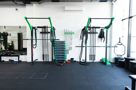 Gym with modern fitness equipment in cross fit zone with horizontal bar, smith training machine,...