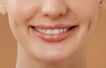 Dental care. Closeup of smiling lady with perfect white teeth, sanding over beige background, cropped shotの写真素材