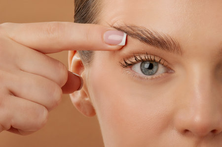 Blepharoplasty. Woman touching eyelid skin and pointing to the wrinkles on the upper eyelid, closeup...