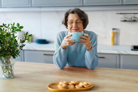 Good morning. Satisfied senior woman drinking hot beverage tea or coffee in kitchen, enjoying calm...