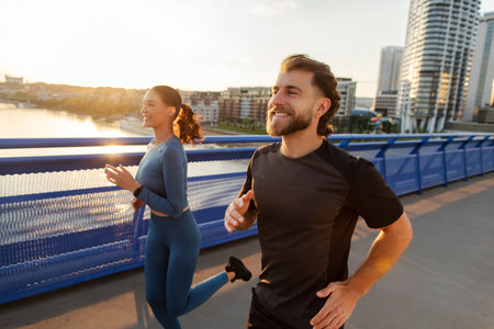 Morning workout. Fast athlete European woman and man running together on city bridge, making sport...