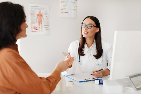 Cheerful female doctor giving her patient pills blister, specialist prescribing middle aged woman treatment, painkiller or vitaminsの写真素材
