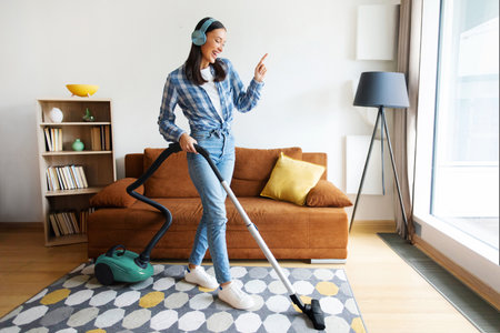 Contented lady enjoy vacuuming tidy room with modern vacuum cleaner and listening music, embodying joyful domestic choresの写真素材