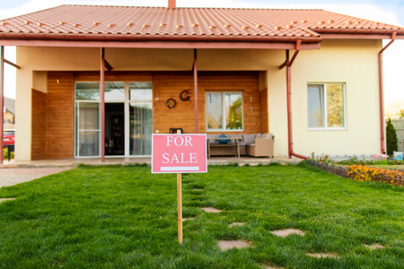 For sale sign outside in front of cozy family house with grassy yard, free space