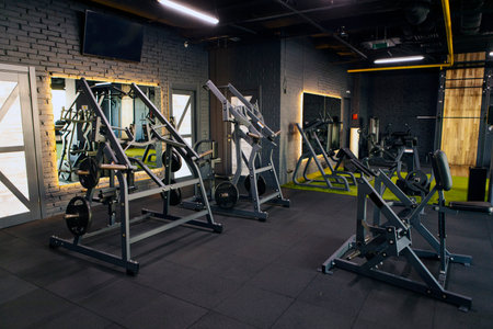 Gym features spacious layout with various weightlifting machines and cardio equipment, well-lit...
